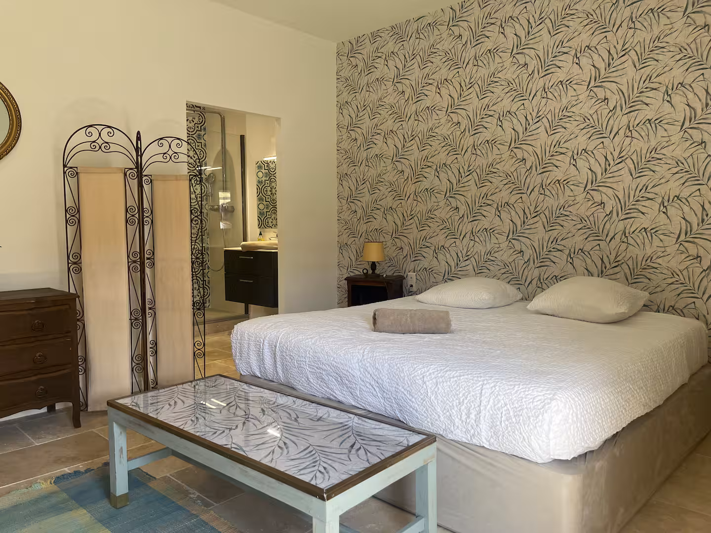 The Olive Room — king-size bed with floral linen, exposed stone wall and rattan pendant lights