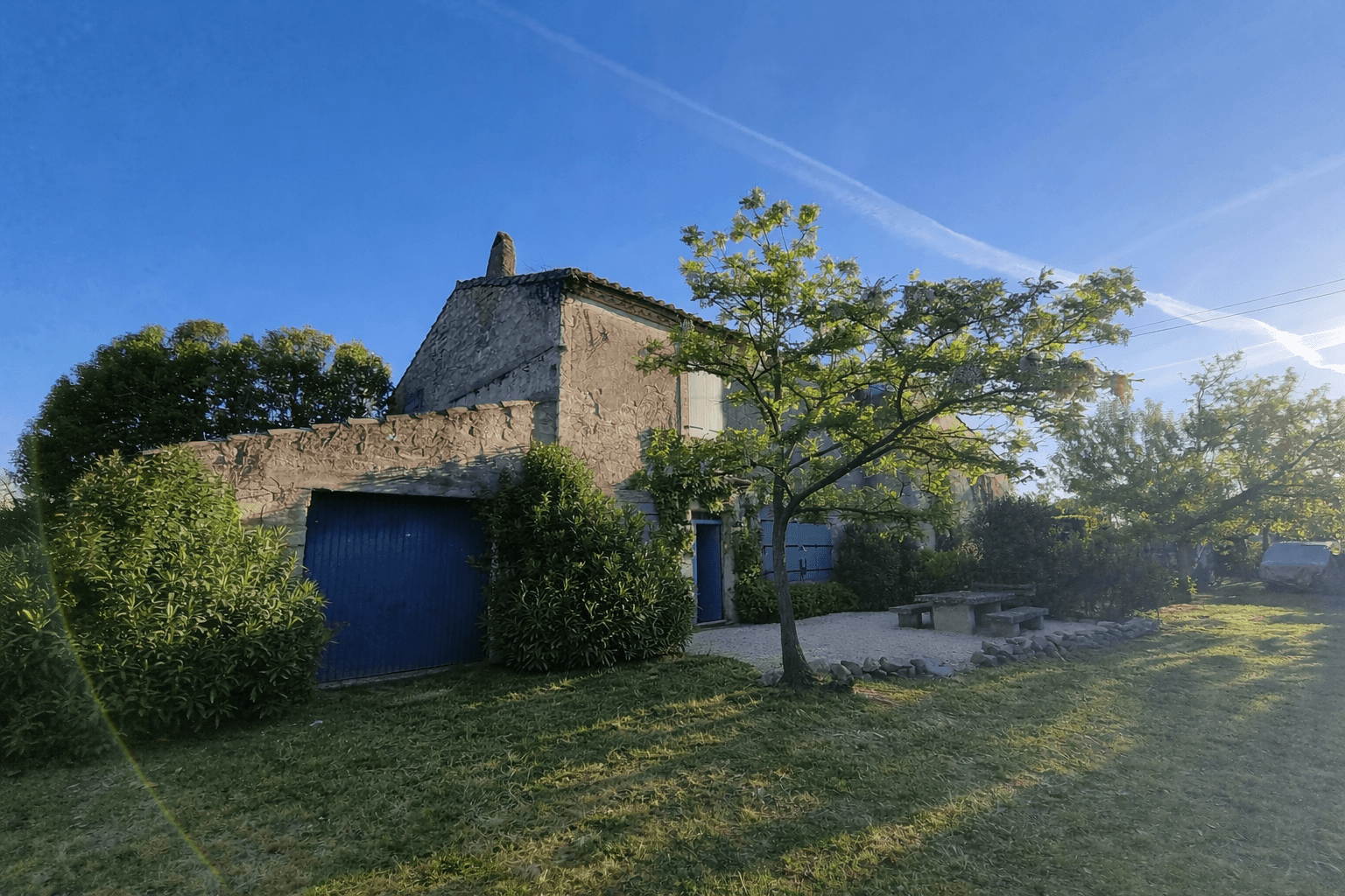 The stone farmhouse in warm golden evening light with fig tree and lawns