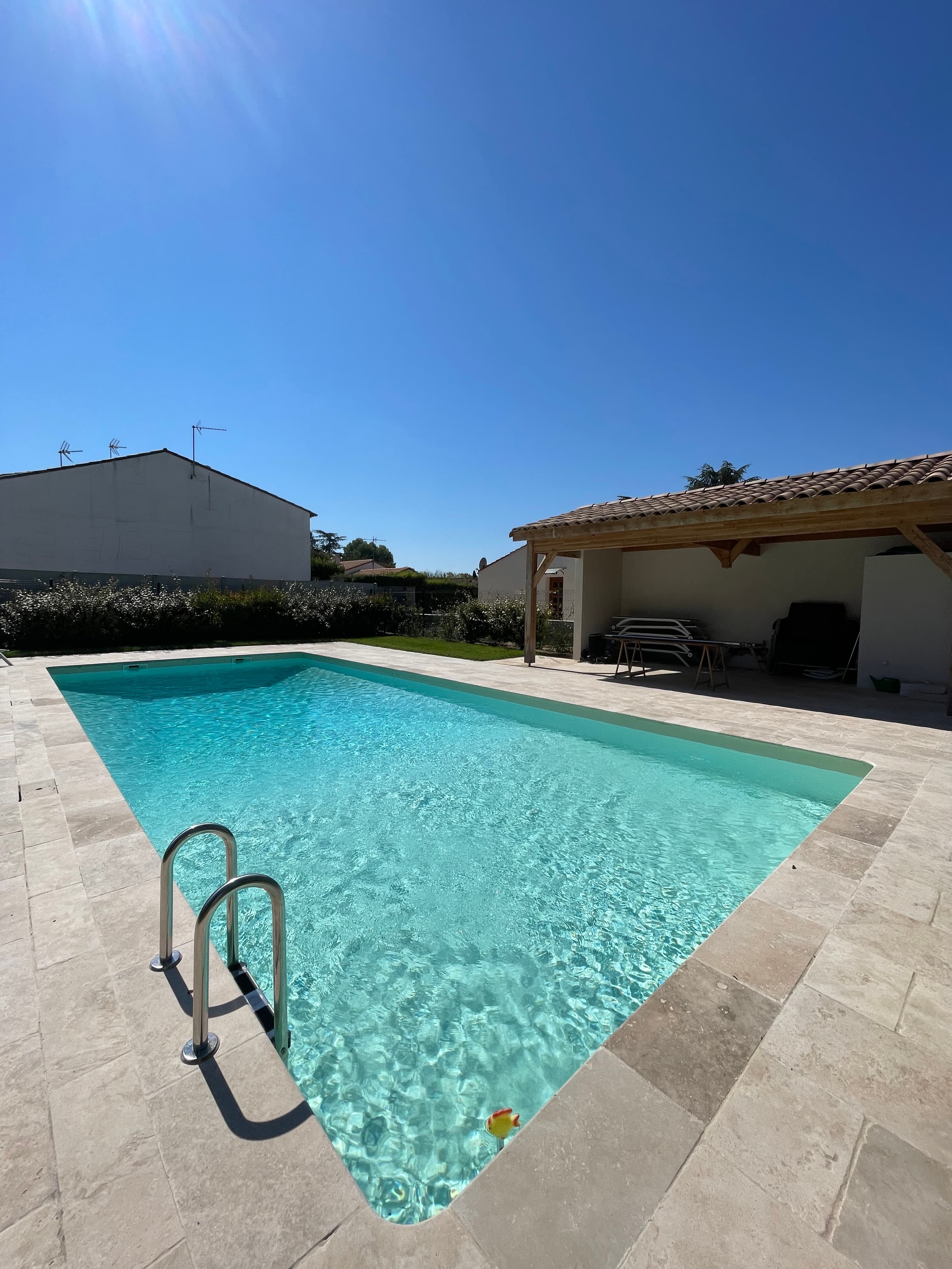 Wide view of the full pool from the shallow end with pool house beyond