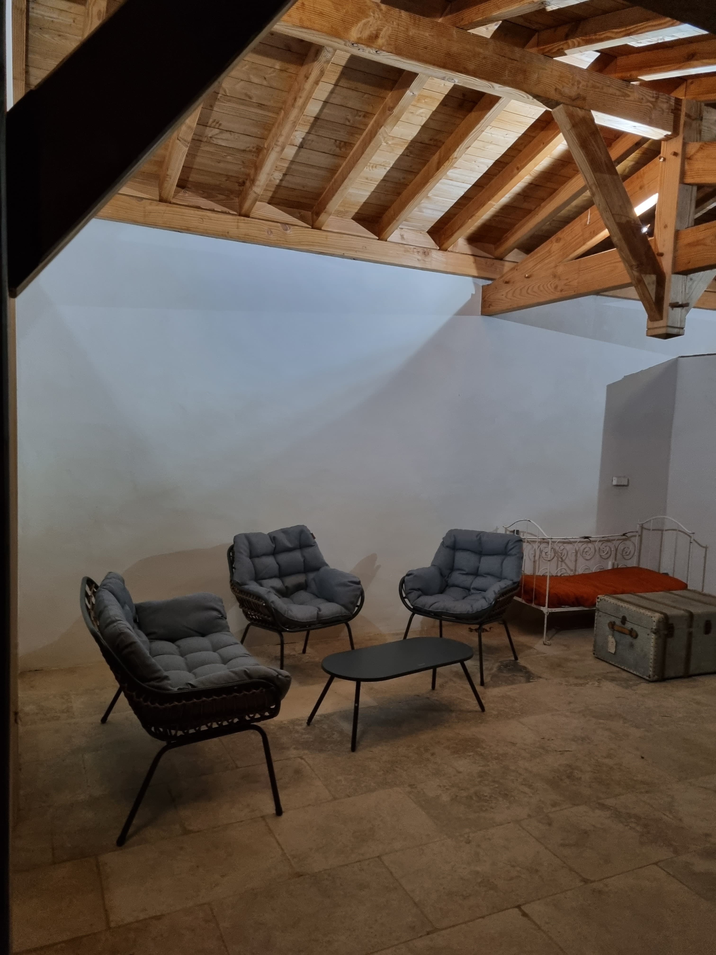 Pool house interior with four rattan armchairs and a vintage iron day bed
