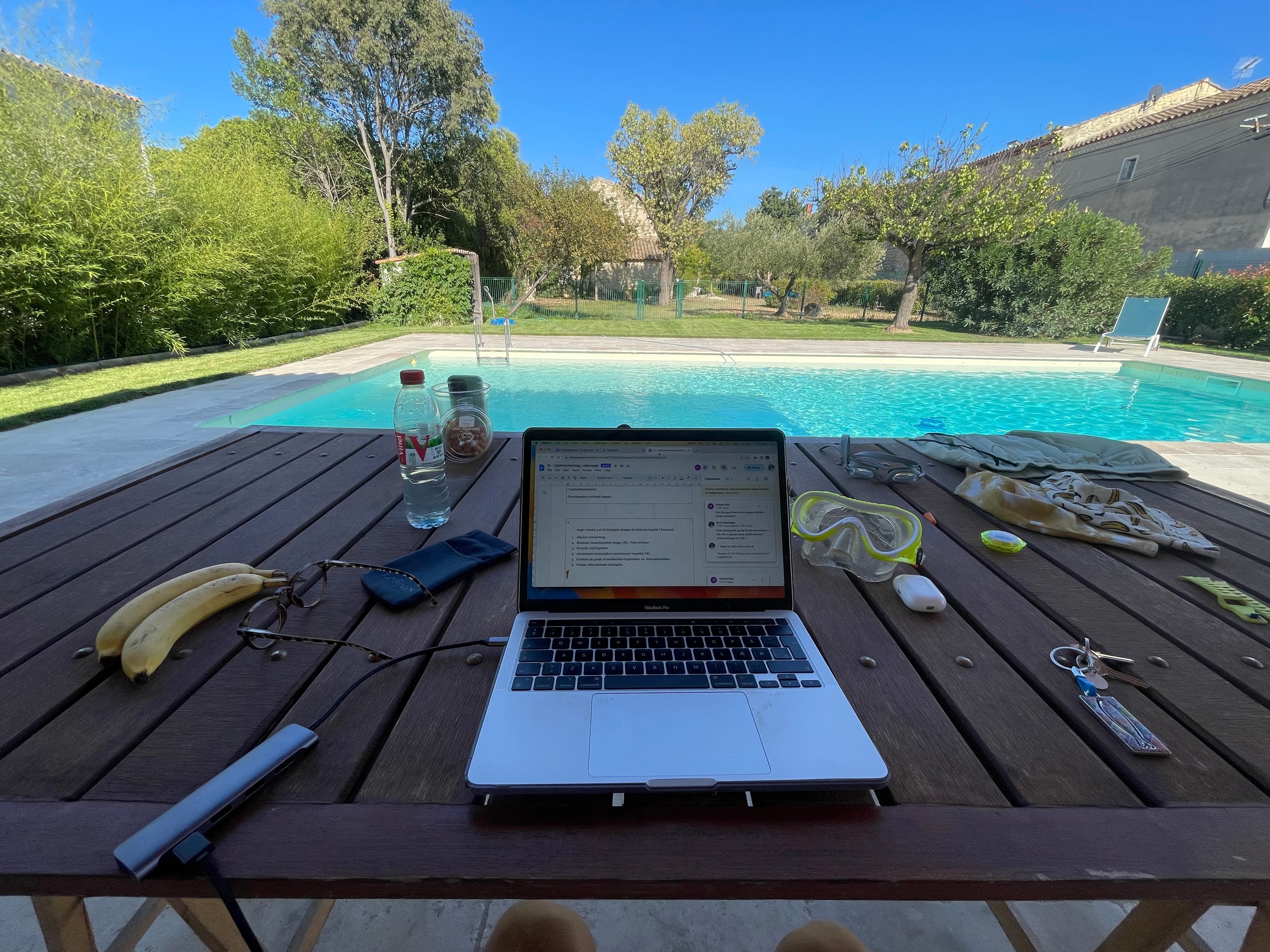 Garden table poolside with the pool and lush garden stretching beyond